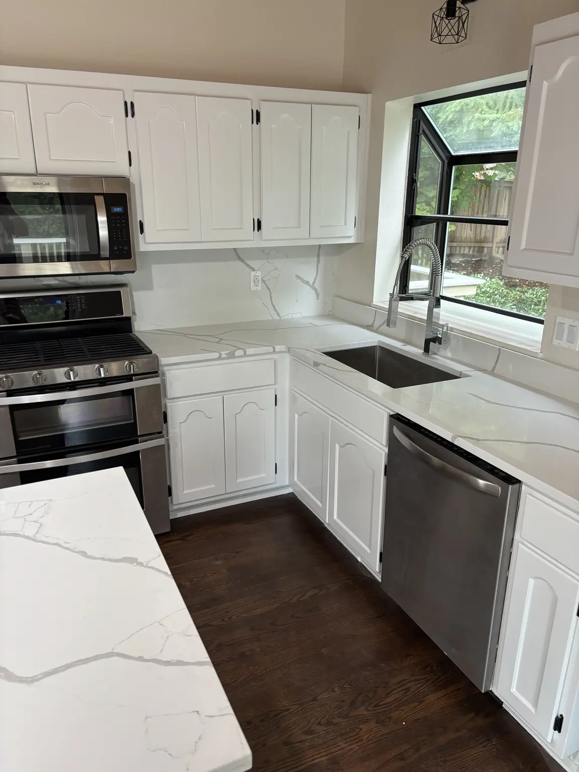 Finished economical kitchen remodel with white cabinets, quartz-style countertops, new sink and faucet