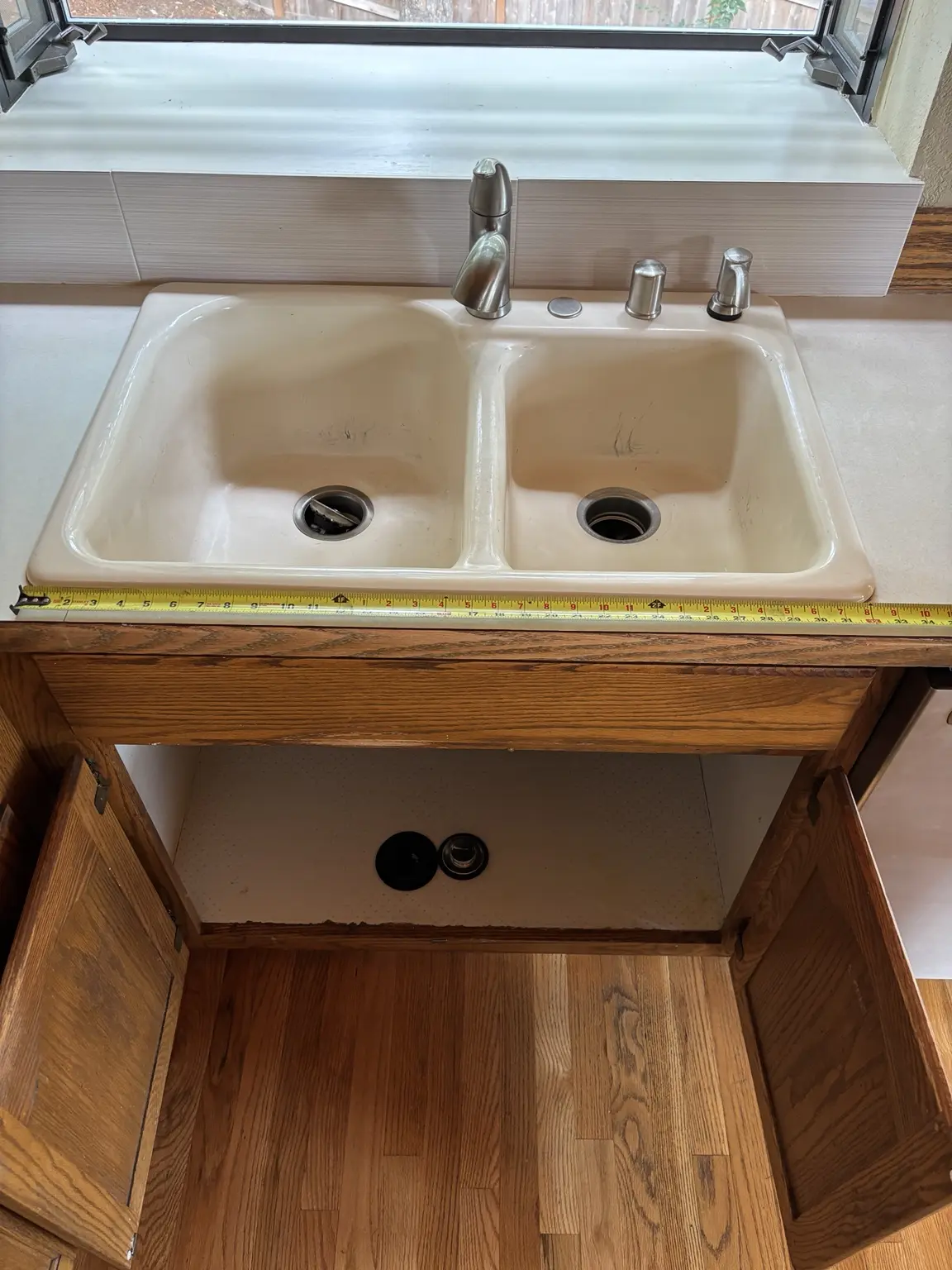 Measuring the original double-basin kitchen sink before replacement
