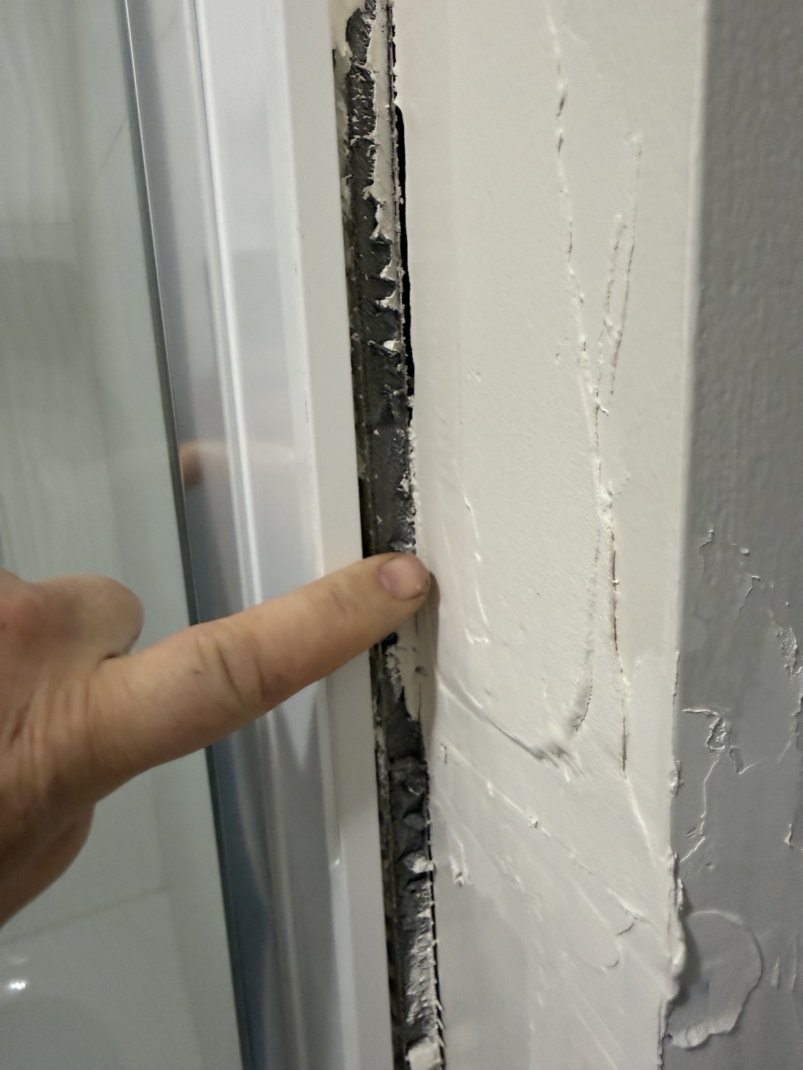 Wide view of the exposed three-quarter-inch gap beside the shower enclosure before repair