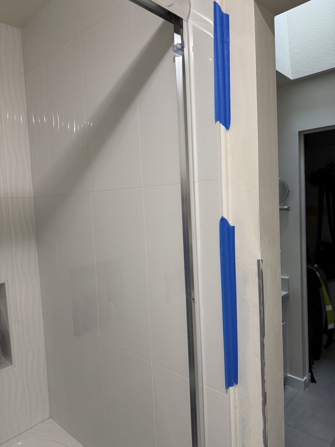PVC trim strip dry-fitted beside the shower and held with painter's tape